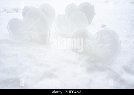 Viele Herzen - ein Symbol der Liebe, aus Eis, stehen in einer Schneeverwehung. Valentinstag. Romantisches Konzept. Stockfoto