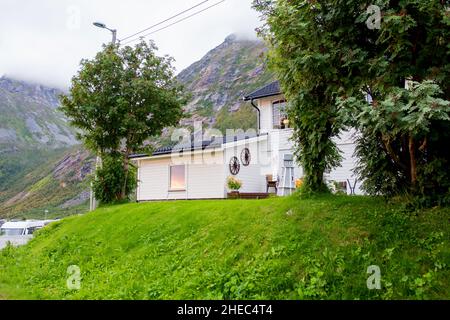 Luftaufnahme von Husoy, einem kleinen Dorf auf einer winzigen Insel, die zur großen Insel Senja gehört und von einer wunderschönen Berglandschaft umgeben ist Stockfoto
