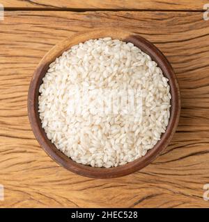 Roher Carnaroli-Risotto-Reis in einer Schüssel über einem Holztisch. Stockfoto