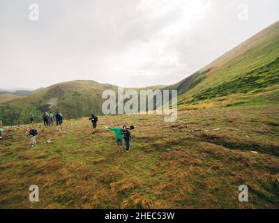 Luftaufnahme des Great Green Ridge. Guy und Girl stehen auf einem großen Hügel vor dem Hintergrund einer riesigen Berglandschaft Stockfoto
