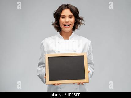 Lächelnde Köchin mit schwarzer Tafel Stockfoto