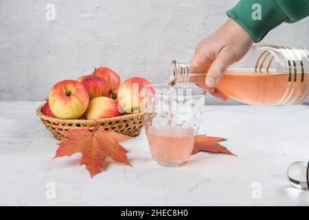 Die Hand einer Frau gießt Apfelessig in ein Glas Stockfoto