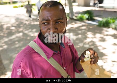afroamerikanischer Geschäftsmann, der auf dem Weg ins Büro einen Snack zu sich nehmen muss Stockfoto