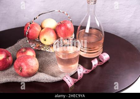 Draufsicht auf einen Holztisch mit einem Glas Apfelessig mit Maßband und Äpfeln. Das Konzept der Gewichtskontrolle Stockfoto