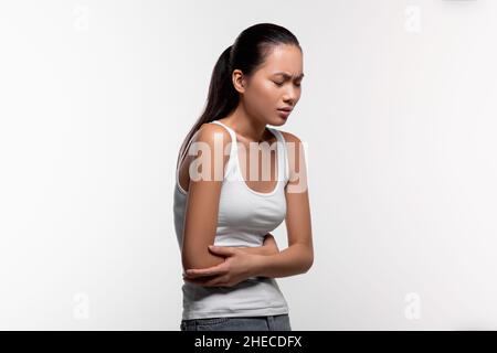 Koreanische Frau mit Schmerzen, die ihren Bauch berührt, Lebererkrankung Konzept Stockfoto