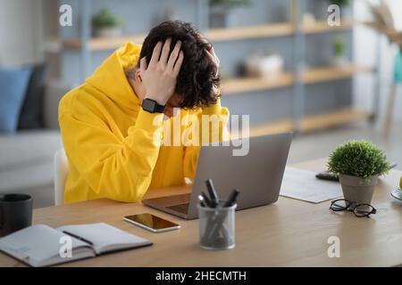 Gestresster asiatischer Mann, der am Schreibtisch mit pc sitzt Stockfoto