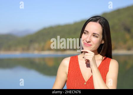 Nachdenkliche Frau, die in der Natur einen sonnigen Tag sieht Stockfoto