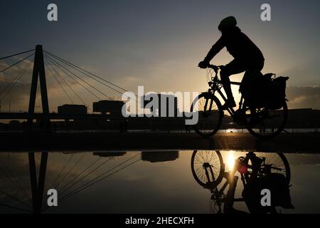 Köln, Deutschland. 10th Januar 2022. Ein Radfahrer fährt in der Abendsonne am Rheinufer entlang. Quelle: Oliver Berg/dpa/Alamy Live News Stockfoto