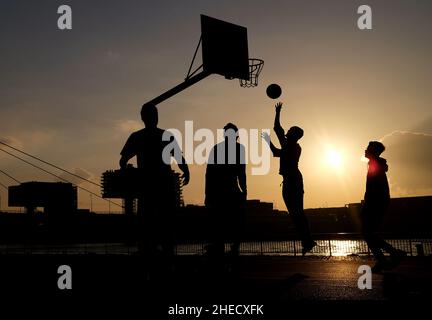 Köln, Deutschland. 10th Januar 2022. In der Abendsonne am Rheinufer spielen Jugendliche Basketball. Quelle: Oliver Berg/dpa/Alamy Live News Stockfoto