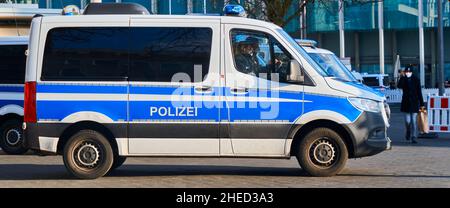 Braunschweig, 8. Januar 2022: Seitenansicht eines deutschen Polizeiwagens, eines blau-weiß lackierten Mercedes-Benz Lieferwagens, der auf dem Bürgersteig und auf dem Mannesfeld geparkt ist Stockfoto