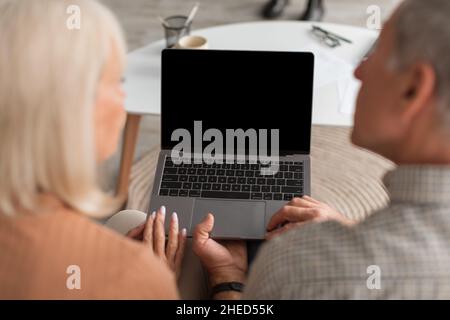 Rückansicht Eines Älteren Ehepaares Mit Laptop Und Leerem Bildschirm Im Innen-Modus Stockfoto