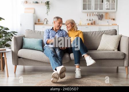 Ältere Paare, Die Einen Laptop-Computer Zu Hause Auf Der Couch Sitzen Stockfoto