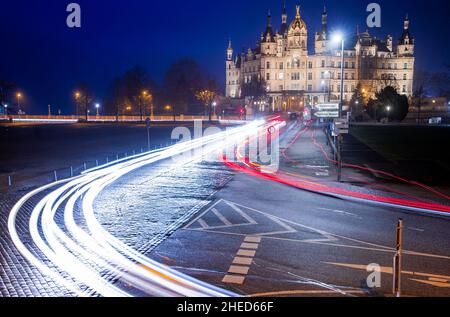 Schwerin, Deutschland. 10th Januar 2022. Autos fahren am Abend am Schweriner Schloss vorbei (Langaufnahme). Das Schloss war jahrhundertelang die Residenz der Herzöge und Großherzöge von Mecklenburg und ist heute Sitz des landtags von Mecklenburg-Vorpommern. Quelle: Jens Büttner/dpa-Zentralbild/dpa/Alamy Live News Stockfoto