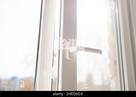 Weißes Kunststoff pvc-Fenster mit Waldhintergrund zu Hause. Sonnenstrahl durch Glas Stockfoto