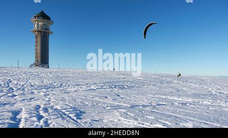 Feldberg, Deutschland - 19. Dezember 2021: 1 Wintersportler im Schnee. Schneekiter mit Rucksack auf Skiern vor blauem Himmel. Feldbergturm auf einem sonnigen ww Stockfoto