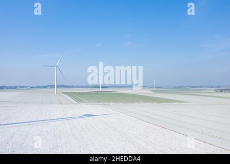 Dieses Landschaftsfoto wurde im Winter in Europa, Frankreich, der Normandie, zwischen Dieppe und Fecamp aufgenommen. Wir sehen vier Windturbinen inmitten eines verschneiten f Stockfoto