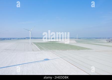 Dieses Landschaftsfoto wurde im Winter in Europa, Frankreich, der Normandie, zwischen Dieppe und Fecamp aufgenommen. Wir sehen die Windkraftanlagen mitten in einer verschneiten Fi Stockfoto