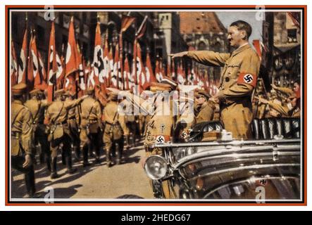 Sturmabteilung Adolf Hitler Saluting SA Trupps Vintage Nazi Deutschland c1935. Nürnberger Kundgebung, farbige Fotokarte von Adolf Hitler mit Hakenkreuzarmband in offenem Mercedes und SA-Truppen, die mit Hakenkreuzfahnen vorbeimarschierten, Verlag H. Wiedemann ,Sturmabteilung die offizielle Uniform der SA war das braune Hemd mit brauner Krawatte 'The Brown Shirts'. Stockfoto