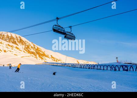 Alpe d'Huez, Frankreich - 30.12.2021 : Skiliftseilbahn am Abend auf alpinem Bergwintergebiet. Ski Sessellift Seilbahn mit Menschen. Typisch fren Stockfoto