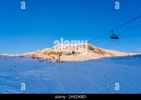 Alpe d'Huez, Frankreich - 30.12.2021 : Skiliftseilbahn am Abend auf alpinem Bergwintergebiet. Ski Sessellift Seilbahn mit Menschen. Typisch fren Stockfoto