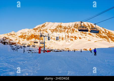 Alpe d'Huez, Frankreich - 30.12.2021 : Skiliftseilbahn am Abend auf alpinem Bergwintergebiet. Ski Sessellift Seilbahn mit Menschen. Typisch fren Stockfoto