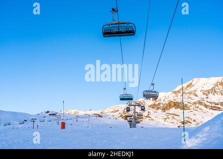 Alpe d'Huez, Frankreich - 30.12.2021 : Skiliftseilbahn am Abend auf alpinem Bergwintergebiet. Ski Sessellift Seilbahn mit Menschen. Typisch fren Stockfoto