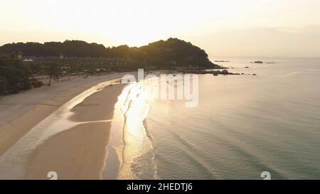 Bäume wachsen auf einem Felsen, umgeben von Meer auf Sonnenuntergang Himmel Hintergrund. Klippe bedeckt von grünen Bäumen auf wunderschönem Meereshintergrund. Stockfoto