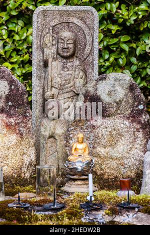 Kleine buddha-Statue mit Münzopfern zu Füßen, dahinter zwei größere Jizo-Statuen, im Saisho-in Garten, Nanzen Tempel. Kyoto. Stockfoto