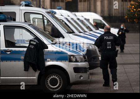 Köln, Deutschland. 10th Januar 2022. Polizeiautos und Polizeibeamte stehen auf dem Roncalliplatz. In Köln gingen am Montagabend mehr als 1000 Menschen gegen die Corona-Maßnahmen auf die Straße. Quelle: Federico Gambarini/dpa/Alamy Live News Stockfoto