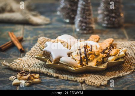 Weihnachtsplätzchen auf einem sternförmigen Teller mit weihnachtsdekoration und Zimtstangen Stockfoto