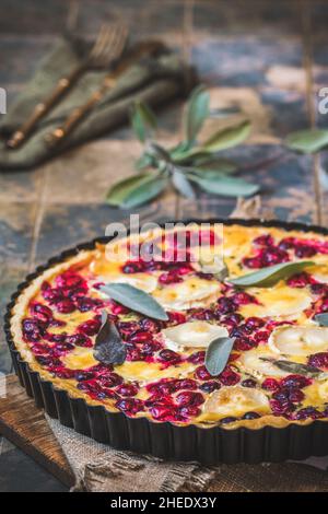 Cranberry Ziegenkäse-Tarte mit Salbei auf rustikalem blauen Hintergrund, vertikal Stockfoto