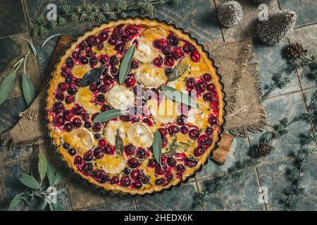 Cranberry Ziegenkäse-Tarte mit Salbei auf rustikalem blauen Hintergrund, Draufsicht Stockfoto