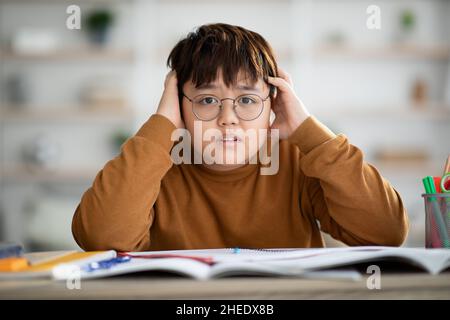 Porträt eines gestressten asiatischen Teenagers, der Hausaufgaben macht Stockfoto