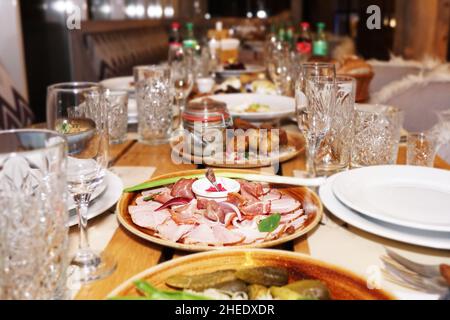 Traditionelles ukrainisches Essen - ein Teller mit Fleisch, gebackene Kartoffeln auf einem Holztisch. Festlicher Tisch Stockfoto