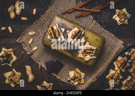 Sternförmige Kekse, eine alte Vintage-Metallkälge, Erdnüsse und Schokolade, Draufsicht. Weihnachts- oder Backszene. Stockfoto