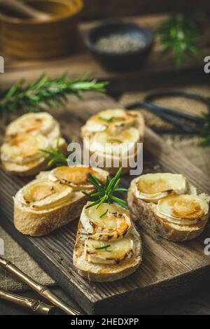 Baguette Brot Scheiben gebacken mit Ziegenkäse und Honig auf Holzhintergrund, vertikal Stockfoto