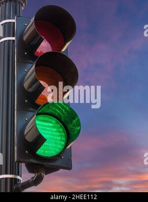 Konzept der Hoffnung und Positivität mit einem Verkehrssignal auf Grün gesetzt gegen einen Sonnenaufgang oder Sonnenuntergang Stockfoto