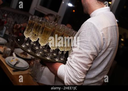 Ein Kellner mit Gläsern mit Champagner serviert auf einer Tablette. Viele Gläser für ein großes Unternehmen Stockfoto