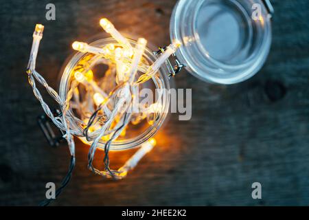 Direkt über Aufnahme von Feenlichtern in einem Glasgefäß auf dunklem Holztisch Stockfoto
