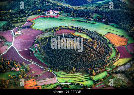 Heißluftballon, der mit dem Vulkan Pujalos und den Bergen im Hintergrund in der Provinz Garrotxa Olot Girona, Katalonien, Spanien, fliegt Stockfoto