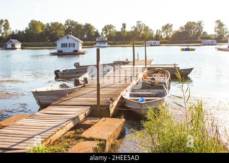 Hausboote im Teich auf dem Lake Erie vom Dock mit Ruderbooten gebunden, um sie an einem Sommertag zur goldenen Stunde zu erreichen Stockfoto