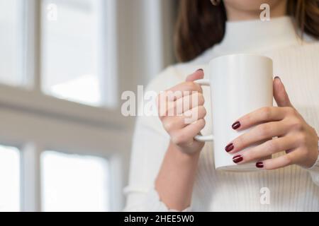 Modell einer weiblichen Hand mit einer Kaffeetasse im Hintergrund des Büros Stockfoto