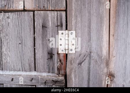 Altes Scharnier an einer hölzernen Scheunentür mit rostigen Nägeln, die auf dem Land aus den Brettern ragen. Abstrakter Hintergrund. Stockfoto
