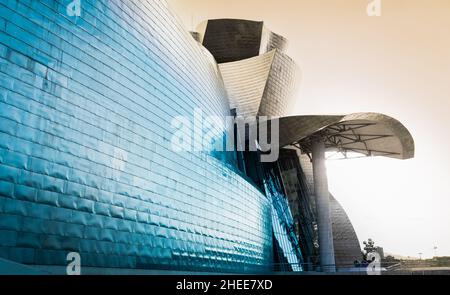 Bilbao, Spanien - 22. April 2021: Fantasievoller Sonnenuntergang im Guggenheim Museum mit Sonnenschein auf einer Titanfassade in Bilbao. Modernes Gebäude Stockfoto