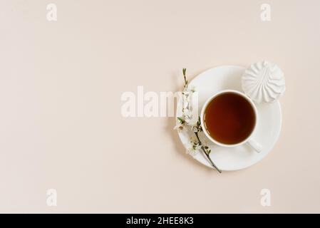 Tasse schwarzen Tee mit Marshmallows und Frühlingsblumen apfelbaum auf beigem Hintergrund mit Kopierraum Stockfoto