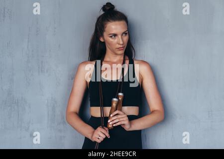 Porträt einer fitgen Frau mit einem Springseil an der Wand. Stockfoto