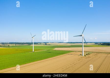 Dieses Landschaftsfoto wurde im Sommer in Europa, Frankreich und der Normandie aufgenommen. Wir sehen zwei normannische Windturbinen mitten in den Feldern von Flachs und Weizen, Stockfoto