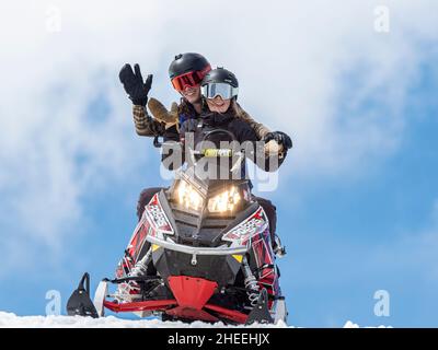 Eine Schneemaschine, die von zwei jungen Fahrern in der Nähe des Beartooth Pass, Wyoming, gefahren wird. Stockfoto