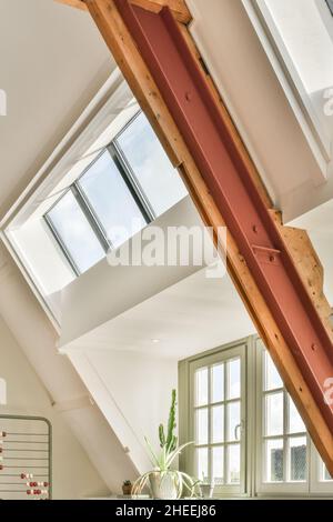 Von unten Blick auf Mansarde Zimmer mit Fenstern und weißen Wänden und Topfpflanzen auf Fensterbank bei Tageslicht platziert Stockfoto