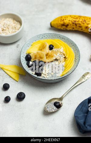 Hoher Winkel von appetitlich gesunden Müsli mit Chiasamen Scheiben Banana Mango und Heidelbeeren zum Frühstück Stockfoto